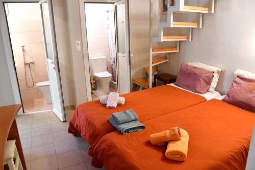 a bedroom with a orange bed with towels on it at Kalokenti Studios in Egina