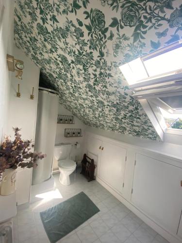 La salle de bains est pourvue de toilettes et de papier peint à fleurs. dans l'établissement Cottage familial avec jardin à Dives-sur-Mer, à Dives-sur-Mer