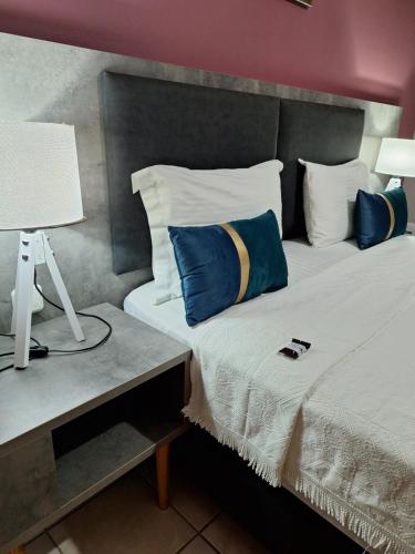 Una cama con almohadas azules y blancas y una lámpara. en Evangelia, en Karfas