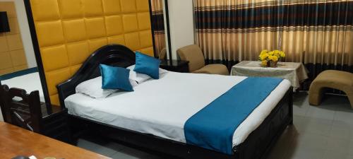 a bedroom with a bed with blue pillows and a table at Hotel Dallas Sylhet in Sylhet