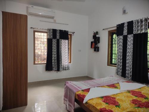 蒙納的住宿－Munnar Village Homes，一间卧室设有一张床和两个窗户。