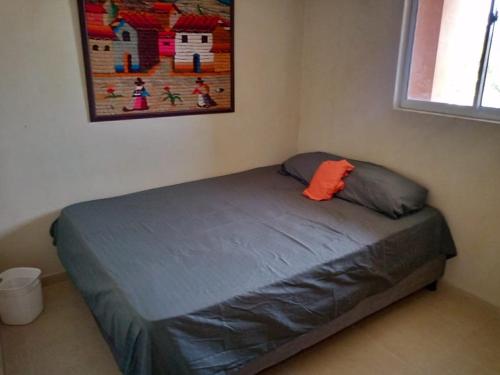 Bett mit orangefarbenem Kissen im Zimmer in der Unterkunft Casa Marcella in Playa Dormida