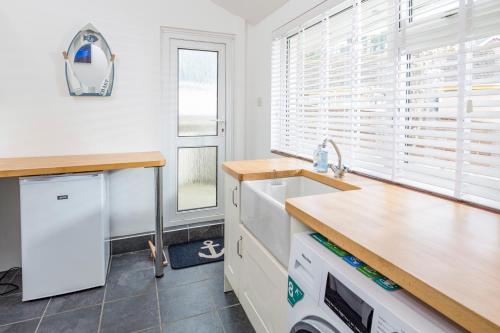 a kitchen with white cabinets and a sink and a window at Rock Point in Salcombe