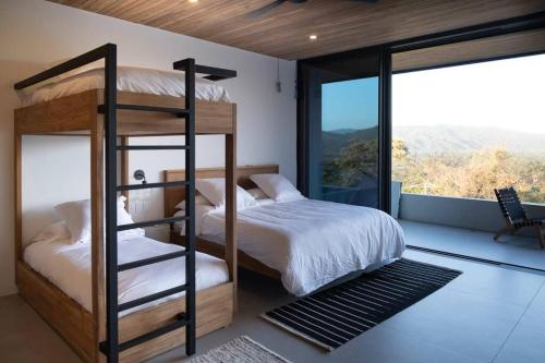 1 Schlafzimmer mit 2 Etagenbetten und einem großen Fenster in der Unterkunft Casa Con Vista – Nosara, Guanacaste, Costa Rica. S in Nosara