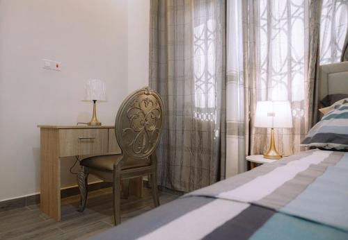 a bedroom with a desk and a chair next to a bed at CMP APARTMENTS in Kasoa