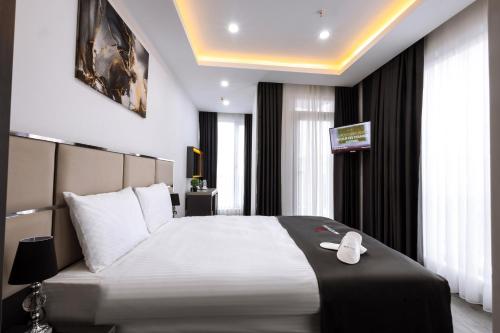 una camera da letto con un grande letto bianco con testiera nera di Meyzi Hotel a Istanbul