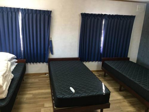 a room with two beds and blue curtains at 千歳空港まで30分/Casa Cotaro（カーサ・コタロ）/最大8名まで宿泊可能/近隣飲食店多数有 in Naganuma