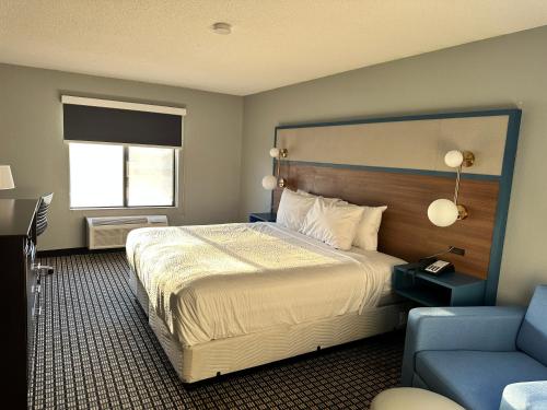 Habitación de hotel con cama y sofá azul en AmericInn by Wyndham Reedsburg, en Reedsburg