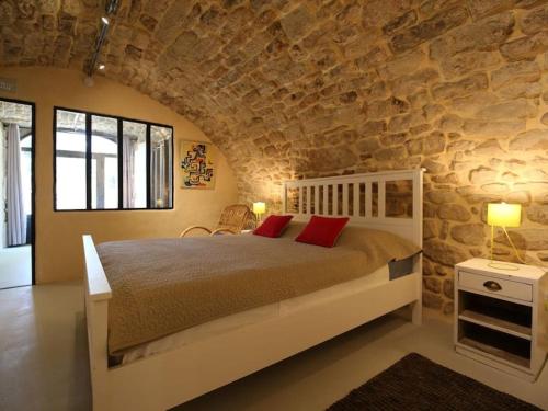 1 dormitorio con cama y pared de piedra en La Salamandre, en Lablachère