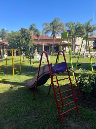 a playground with a slide in a park at Garden House Hotel in Río Cuarto