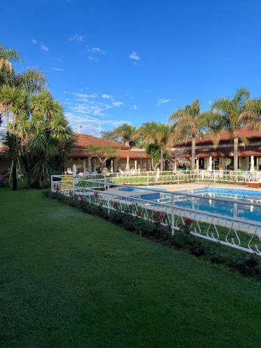 a swimming pool with a resort with palm trees at Garden House Hotel in Río Cuarto