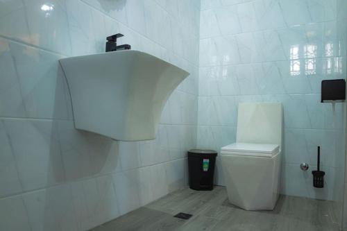 a white bathroom with a toilet and a trash can at CMP APARTMENTS in Kasoa