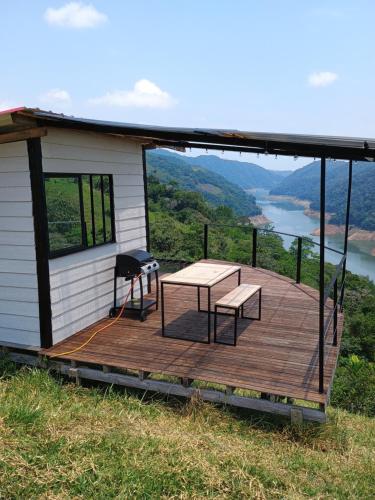 ein Haus mit einer Terrasse mit einem Tisch und einer Bank in der Unterkunft COCOZNA Glamping in Norcasia