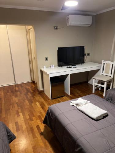 a room with a bed and a desk with a television at Garden House Hotel in Río Cuarto