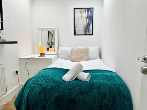 a bedroom with a bed with a green blanket at 7-mins to Central London, Premium 3-bedroom Getaway, Sleeps 7, Free Parking in London