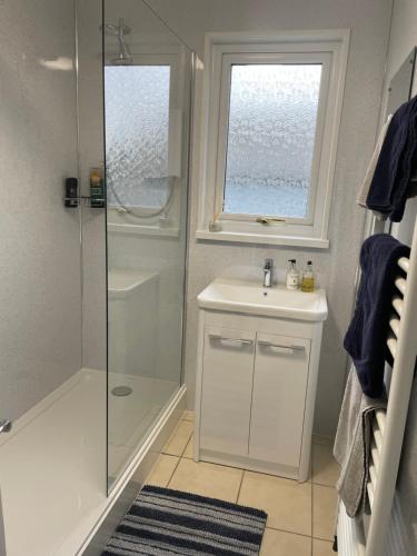 a bathroom with a shower and a sink and a window at Broadsea in Inverurie