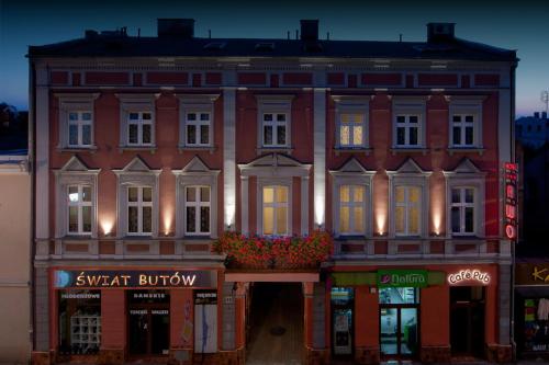 een groot gebouw van rode baksteen met een verlichte gevel bij Hotel Awo in Gniezno