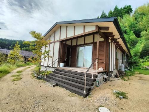 ein kleines Haus mit einer Veranda und einer Treppe dahin in der Unterkunft 能登島ゲストハウスうたたね in Nanao