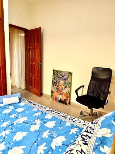 a bedroom with a bed and a chair and a painting at Grandiose apart in yaounde in Yaoundé