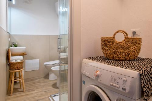 アルゲーロにあるC & C Holidaysの上部にバスケットが付いた洗濯機を備えたバスルーム
