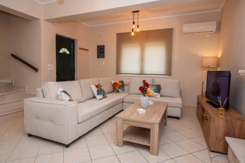 a living room with a white couch and a tv at John & Angelo Villa in Akrotiri