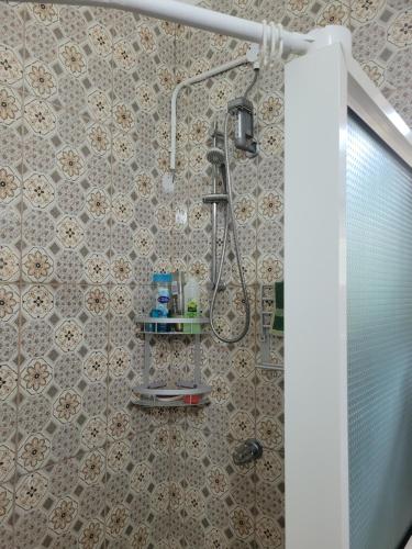 a bathroom with a shower with a tiled wall at Tim's & Mag's Home Stay in Roseau
