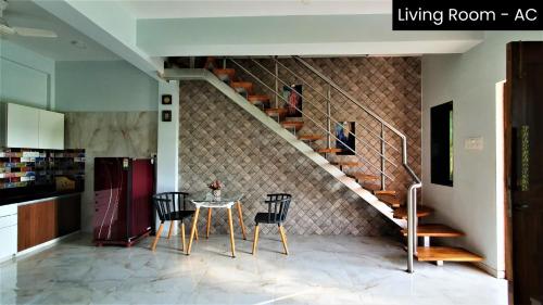 a dining room with a table and a staircase at Nessies in Alibaug