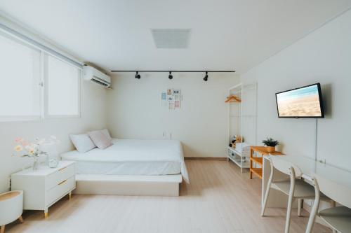a white bedroom with a bed and a desk at DK House in Seoul