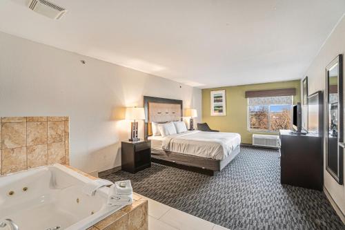 - une chambre d'hôtel avec un lit et une baignoire dans l'établissement Country Inn & Suites by Radisson, South Haven, MI, à South Haven