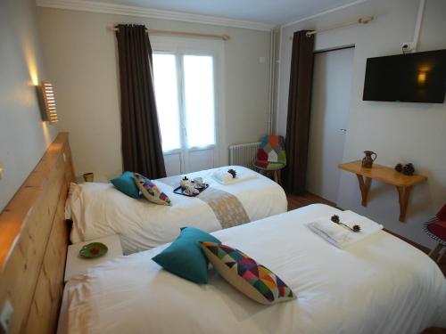 a hotel room with two beds and a television at Auberge Le Tétras Lyre in Vassieux-en-Vercors