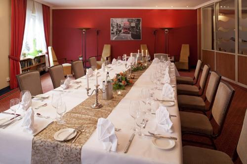a long table in a room with white tables and chairs at HansenS Haus am Meer in Bad Zwischenahn