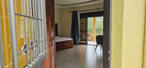a room with a bed and a door to a balcony at Kaije Country Cottages in Fort Portal