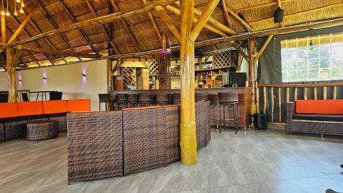 a bar in a restaurant with wooden ceilings and chairs at Kaije Country Cottages in Fort Portal