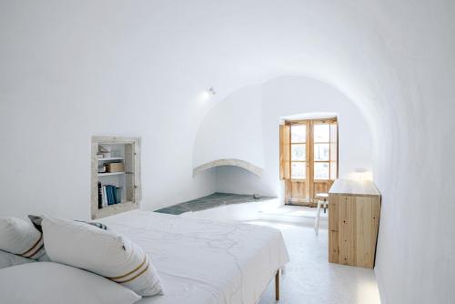 a white room with a bed and a chair at Casa Kombonada in Kýthira