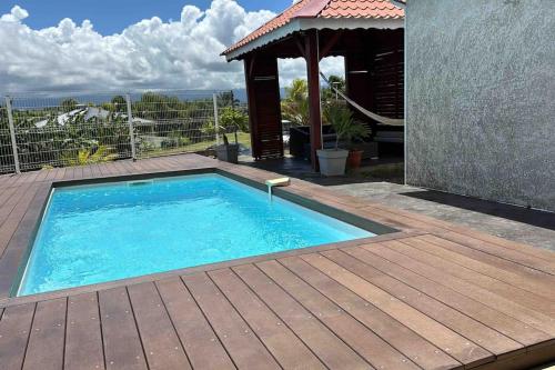 une piscine avec une terrasse en bois et un kiosque dans l'établissement Villa Fusains, à Baie-Mahault