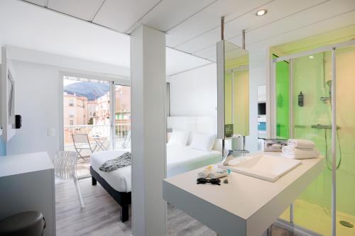 a bedroom with a bed and a bathroom with a sink at Ibis Styles Menton Centre in Menton
