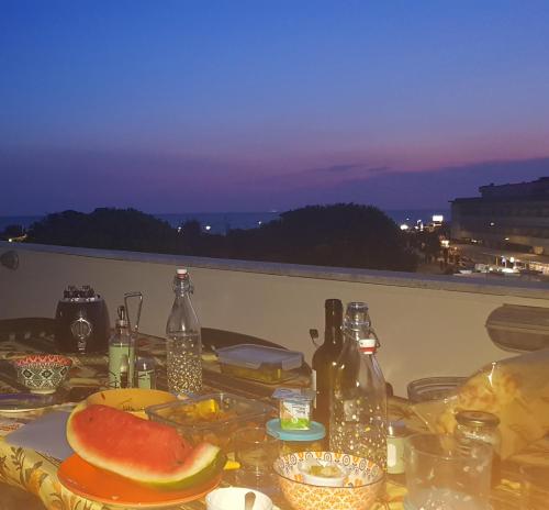 una mesa con comida y botellas en el balcón en Attico Vista Mare, en Tirrenia