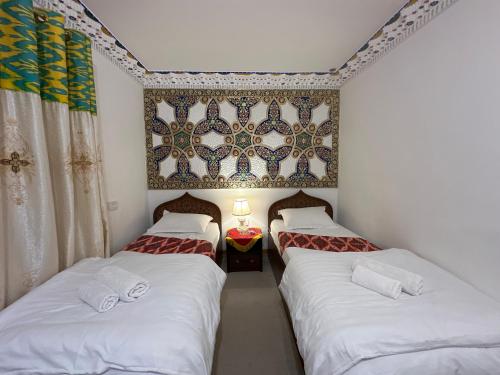 2 camas individuales en una habitación con pared en Rizo Boutique, en Bukhara