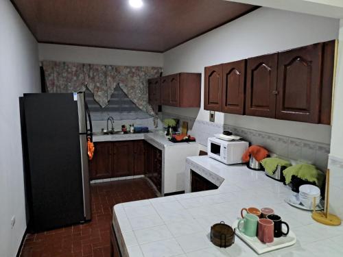 - une cuisine avec des placards en bois et un réfrigérateur noir dans l'établissement Hostel Casa Mar, à Liberia