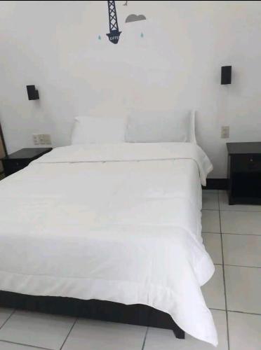 um quarto com uma cama branca com lençóis brancos em Ethan's Vacation House (Camiguin) em Mambajao