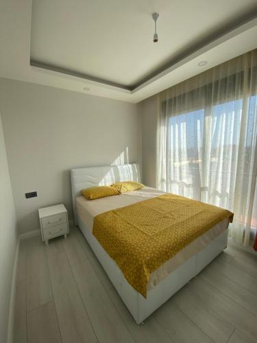 ein Schlafzimmer mit einem Bett und einem großen Fenster in der Unterkunft Antalya Havalimanına Yakın Havuzlu 1+1 Lux Daire in Antalya