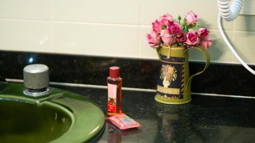 a vase of pink flowers next to a sink at Canto das Laranjeiras Beach Club Guaiuba in Guarujá