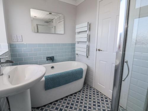 a bathroom with a tub and a sink and a mirror at 107 Gronant Road in Prestatyn