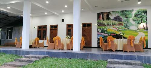 une table et des chaises devant un bâtiment orné d'une fresque murale dans l'établissement Avanya Hotel And Reception Hall, à Angunakolapelessa