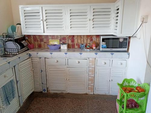 a kitchen with white cabinets and a microwave at Samia House in Malindi
