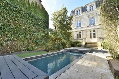 a swimming pool in a garden next to a building at Hôtel particulier Le Trémolières in Cholet