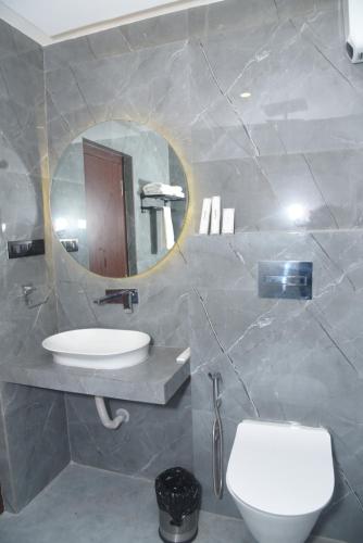 uma casa de banho com um lavatório, um espelho e um WC. em HOTEL LAWANG SIGNAGE em Deoghar