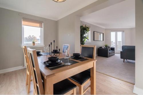 uma sala de jantar e sala de estar com mesa e cadeiras em Penthouse at the Bay near Edinburgh em Saint Davids