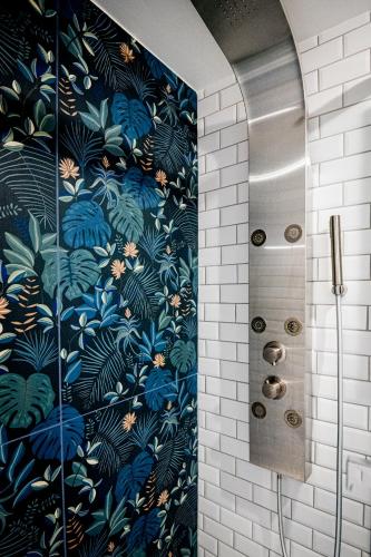 La salle de bains est pourvue d'une douche et de papier peint floral bleu. dans l'établissement La Luciole, à Honfleur