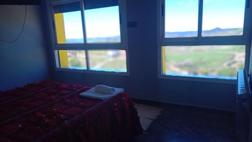 a bedroom with three windows and a bed with a blanket at Gîte Forest Tagroumte in Azrou